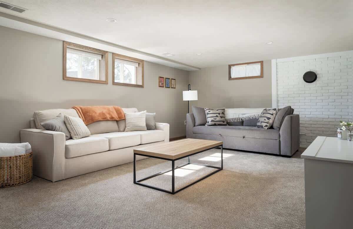 A modern living room with two sofas, a coffee table, and a white brick accent wall.
