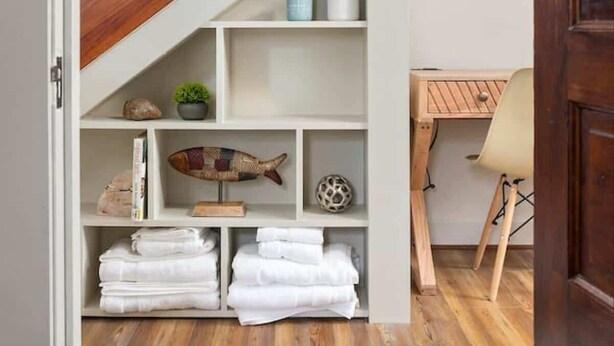 Una escalera con barandillas de madera que conduce a un espacio interior blanco.