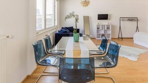Une chambre moderne comprenant une table à manger, des chaises, une plante, un miroir, un téléviseur et un lit.