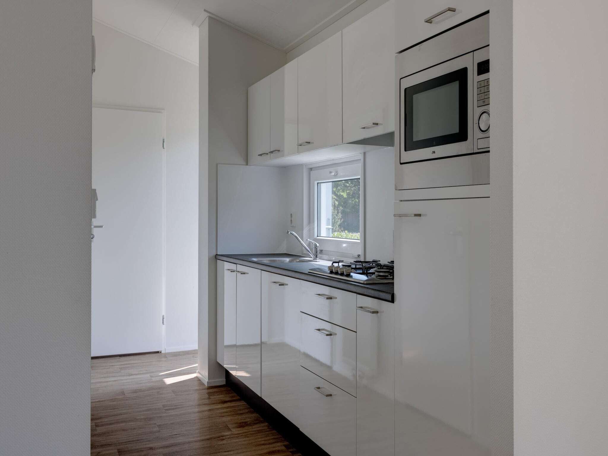 Una cocina moderna con armarios blancos, encimera negra y una ventana sobre el fregadero.