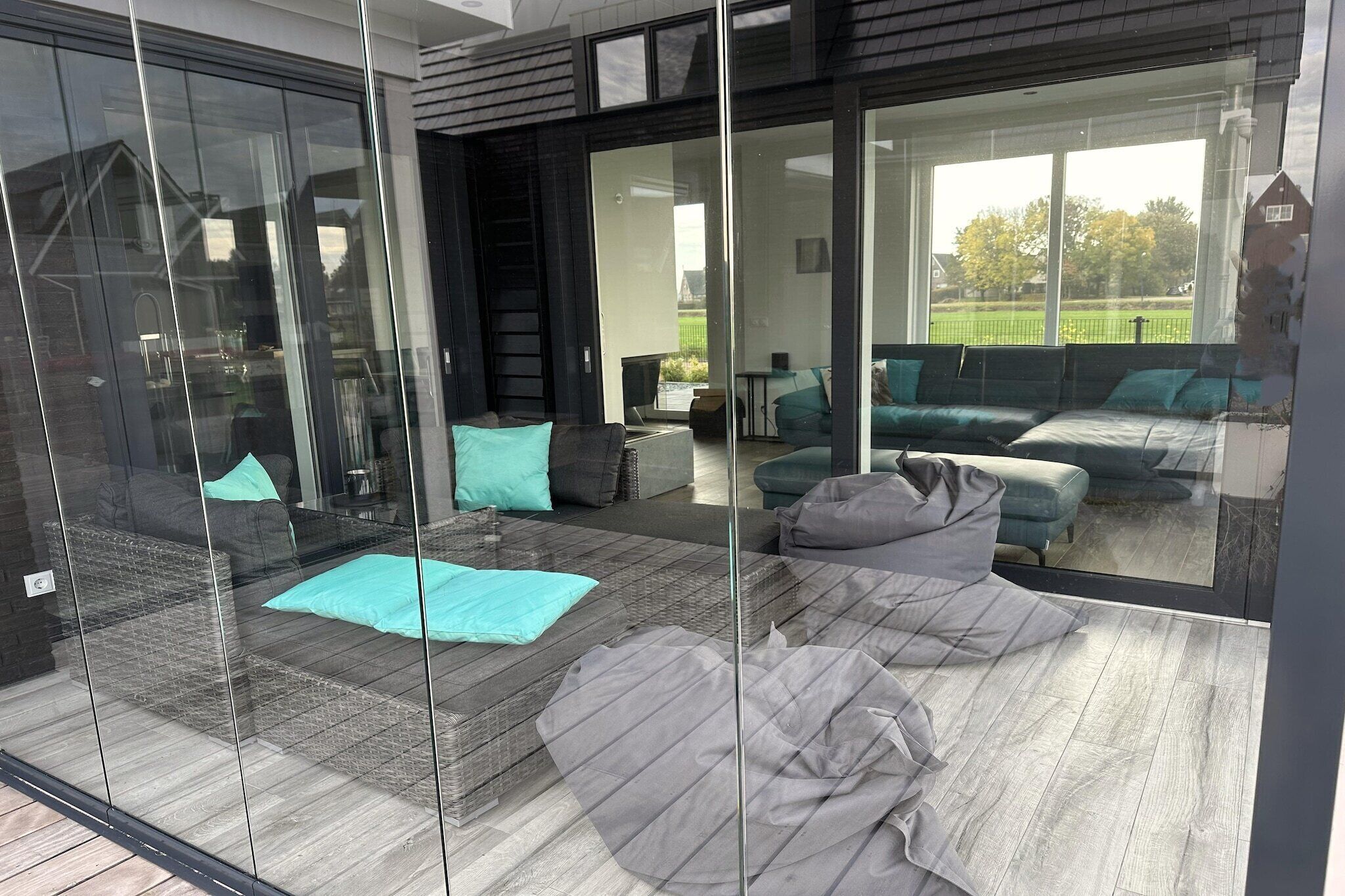 A modern interior with a glass wall, a sofa set, and a dining area.