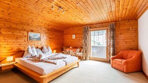 Ein Schlafzimmer einer Holzhütte mit einem Bett, einem kleinen Tisch, einem Stuhl und einer Couch.