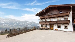 Ein zweistöckiges Gebäude mit Balkon, Holzfassade und Bergblick.
