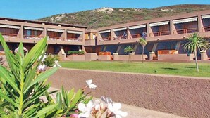 A hotel with multiple balconies, a central courtyard, and a mountainous backdrop.