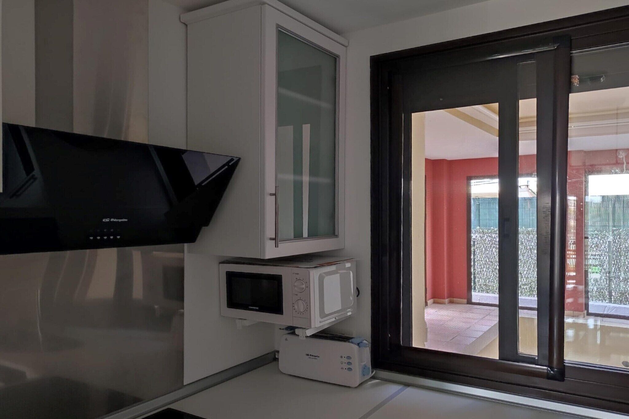A room with a flat-screen TV mounted on the wall, a microwave, and a toaster on the countertop.