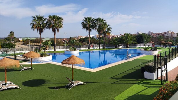 Ein Pool mit Palmen, Liegestühlen und Blick auf eine Stadtlandschaft.