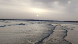 Ein Strand mit Wellen und bewölktem Himmel.