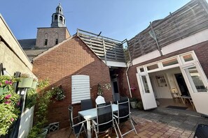 A courtyard with a brick building, a white door, and a table with chairs.