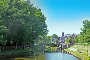 A canal with a bridge, surrounded by lush greenery and traditional buildings. - De Mattelier, Comfortable Holiday Home on the Market (Groenlo)