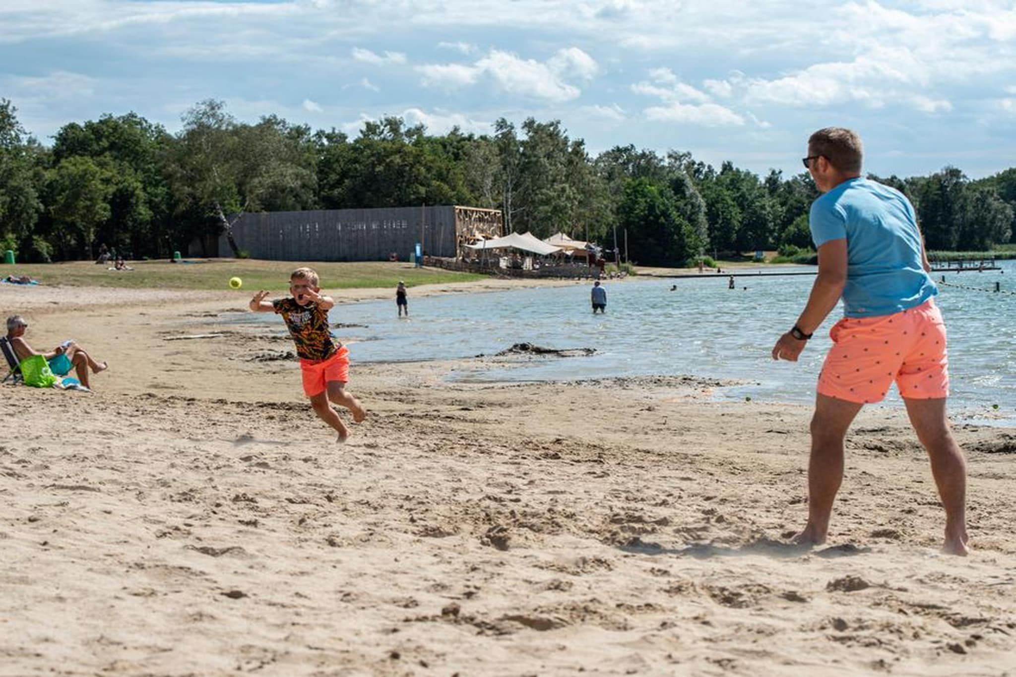 A beach with people playing, a sandy shore, and a body of water.