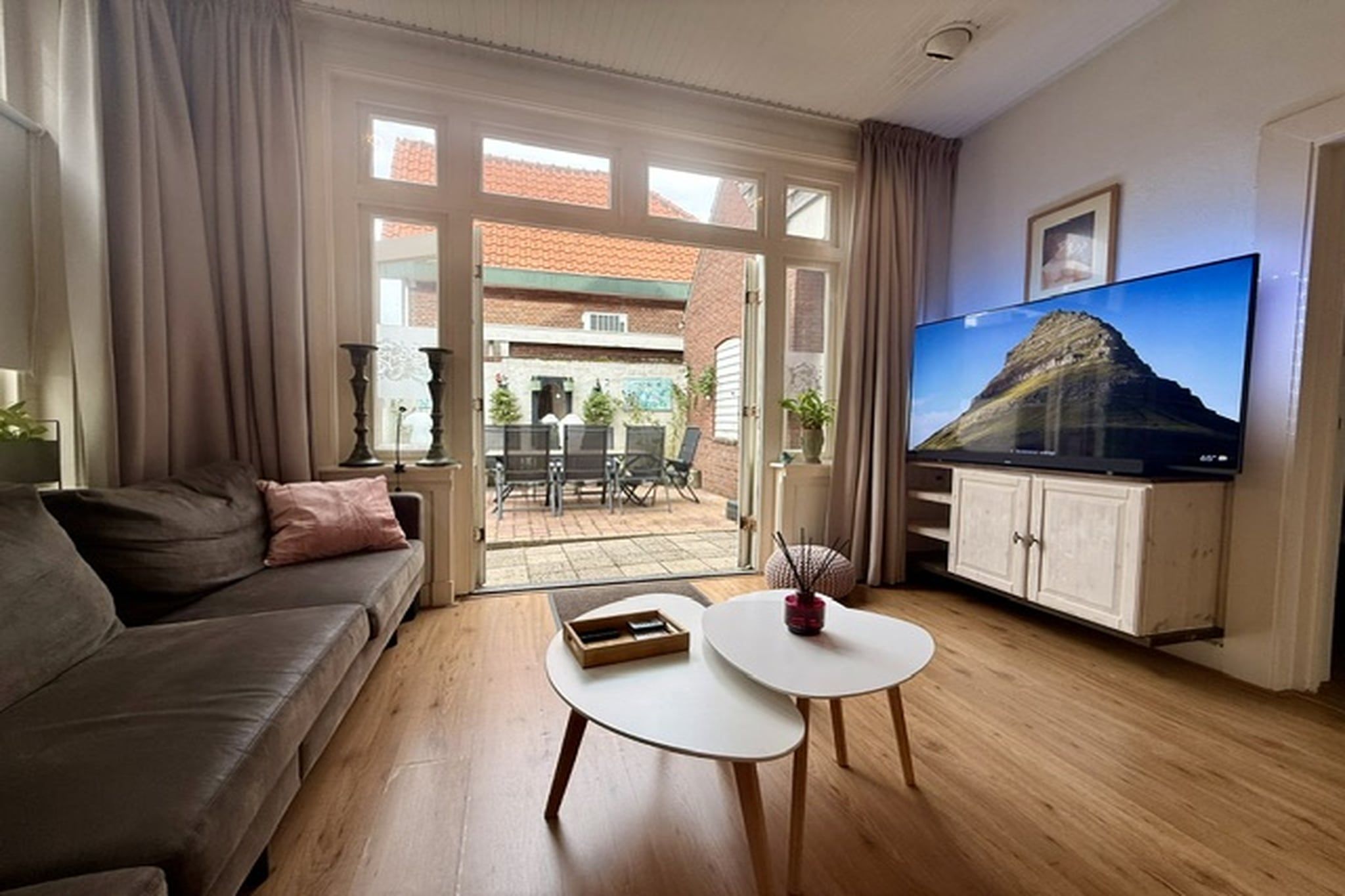 A living room with a sofa, coffee table, TV, and a view of the outside.