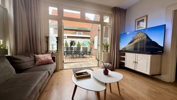 A living room with a sofa, coffee table, TV, and a view of the outside.