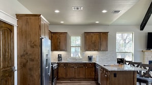 A modern kitchen with wooden cabinets, a central island, and a built-in stove.