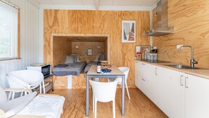 A compact kitchen with a wooden interior, a dining table with chairs, a microwave, and a sink. - Comfortable holiday home in Den Ham with garden (Den Ham)