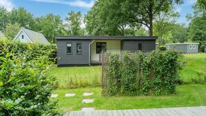 A modern single-story house with a dark exterior, a small front porch, and a well-maintained lawn. - Comfortable holiday home in Den Ham with garden (Den Ham)