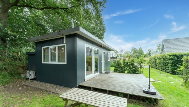 A modern tiny house with a deck, a picnic table, and a satellite dish. - Comfortable holiday home in Den Ham with garden (Den Ham)