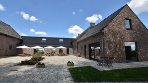 A courtyard with brick buildings, outdoor seating, and a grassy area.
