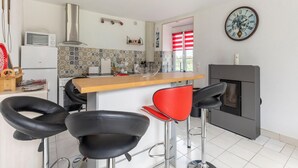 A modern kitchen with a central island, bar stools, a microwave, a stove, and a decorative clock on the wall. - Sunlit Garden Escape Normandy (Isigny sur Mer)