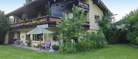 A two-story building with a balcony, outdoor furniture, and a garden.