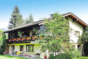 A two-story building with a balcony, outdoor seating, and a sign indicating a restaurant.