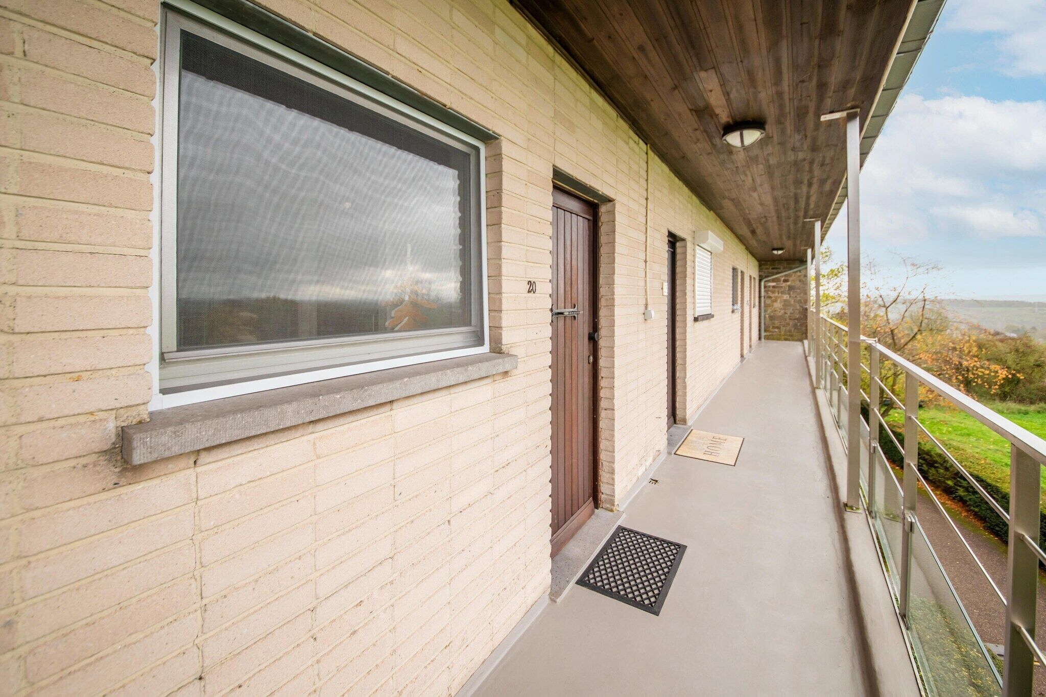 A building with a covered balcony, a large window, and a door.