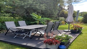A patio with a table and chairs, surrounded by potted plants and a grassy lawn. - charmante Erdgeschosswohnung in Daun (Daun)