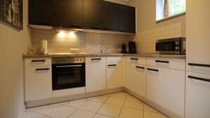 A modern kitchen with white cabinets, a black oven, a microwave, and a coffee maker. - charmante Erdgeschosswohnung in Daun (Daun)
