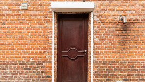 Un mur de briques avec une porte en bois ornée d’une poignée en métal décorative.