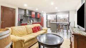 Un salon moderne avec un canapé, une table basse et un coin cuisine doté de meubles rouges et d’une grande fenêtre.