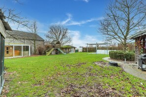 A backyard with a grassy lawn, a wooden play structure, and a house with a glass door.