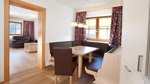 A modern living room with a sofa, a dining table, and a wooden floor. - Apartment Wald im Pinzgau near Ski Lift (Wald im Pinzgau)