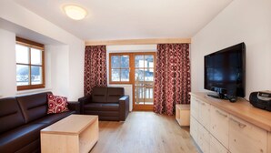 A modern living room with a sofa, a coffee table, a TV, and a wooden cabinet. - Apartment Wald im Pinzgau near Ski Lift (Wald im Pinzgau)