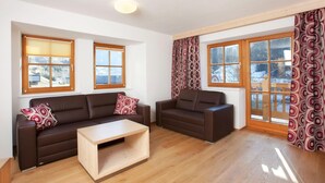 A spacious living room with two sofas, a coffee table, and large windows with curtains. - Apartment Wald im Pinzgau near Ski Lift (Wald im Pinzgau)