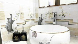 A bathroom with a large white sink, two black bottles labeled 'HuangGuia', and a beige cup on the counter. - Hoang Gia Hotel Dong Tru -by Bay Luxury (Hanoi)