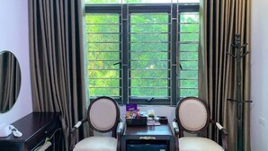A hotel room with two armchairs, a small table, a desk with a telephone, and a window with curtains. - Hoang Gia Hotel Dong Tru -by Bay Luxury (Hanoi)