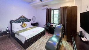 A hotel room with a bed, a desk, a chair, a TV, and a ceiling fan. - Hoang Gia Hotel Dong Tru -by Bay Luxury (Hanoi)
