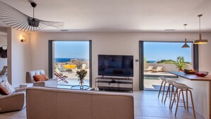 A modern living room with a large TV, comfortable seating, and a view of the sea. - Superb villa with pool and sea view (Monticello)