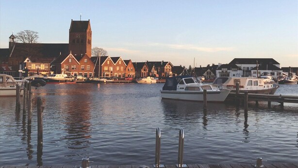 A waterfront area with a church, boats docked at the pier, and traditional buildings along the water.