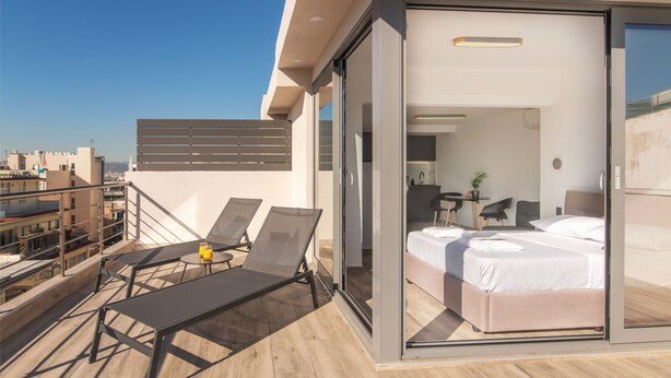 Une chambre d’hôtel moderne avec un balcon, un lit et un petit coin salon.