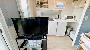 A compact kitchenette with a flat-screen TV, microwave, kettle, and small refrigerator. - Lovely holiday home in Vlaanderen with garden (Vlaanderen)