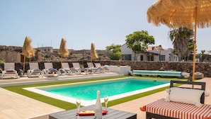 Ein Swimmingpool mit Liegestühlen und einem Tisch mit Getränken.