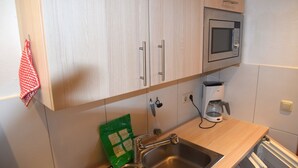 A kitchen with wooden cabinets, a stainless steel sink, a microwave, and a coffee maker. - Comfort with Garden Charm (Füssen)