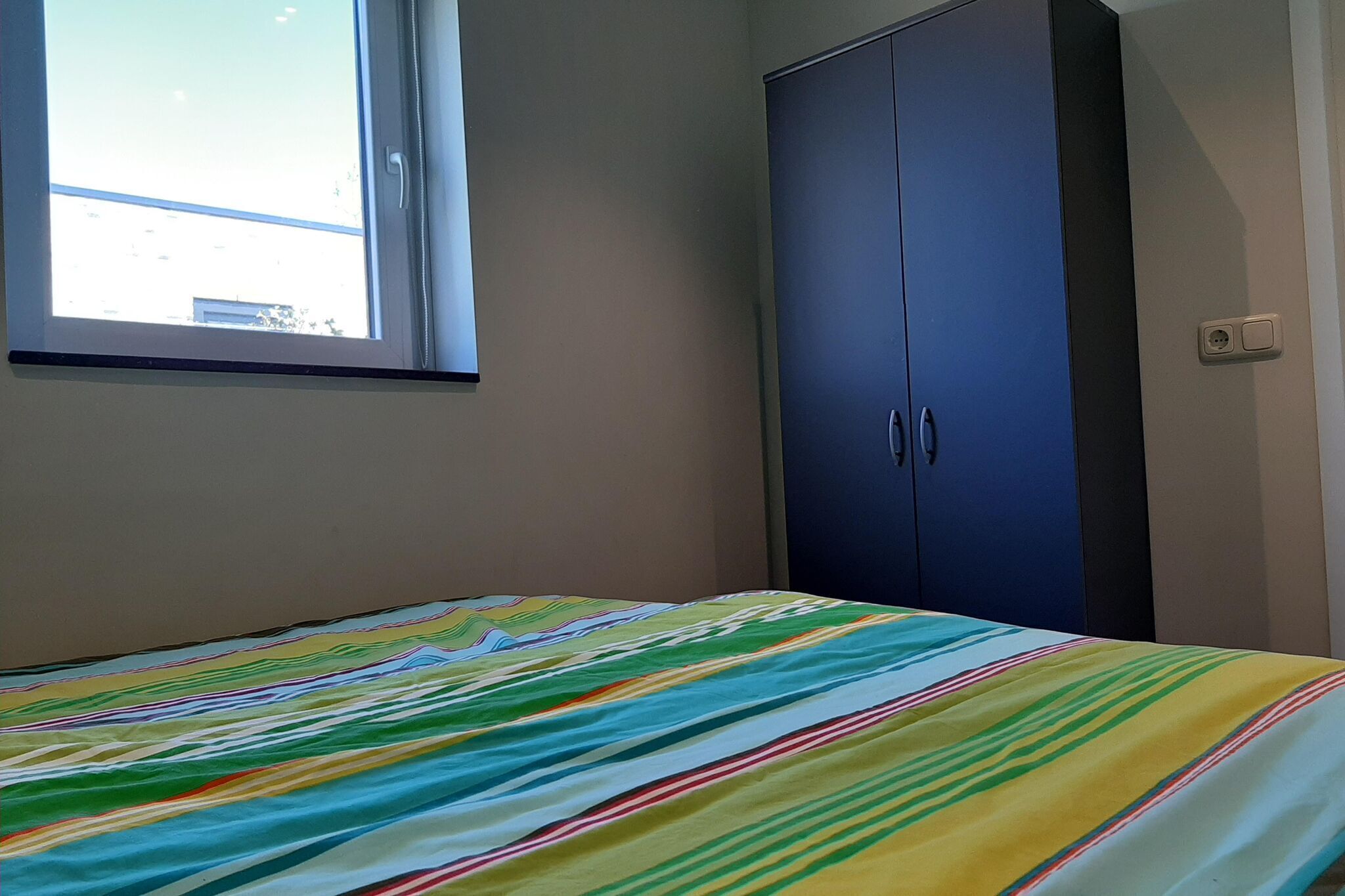 A bedroom with a bed, a window, and a wardrobe.