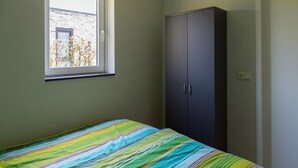 Un dormitorio con cama, ventana y armario.