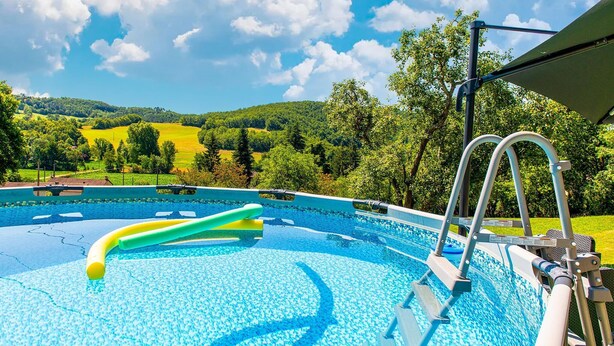 Une piscine avec vue sur des collines verdoyantes et des arbres.