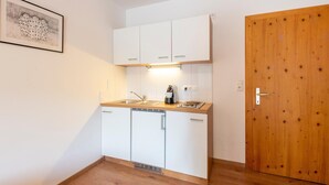 A compact kitchen with white cabinets, a wooden countertop, a coffee machine, and a sink. - Apartment Kirchbichl near Wildschönau Ski Slope (Kirchbichl)