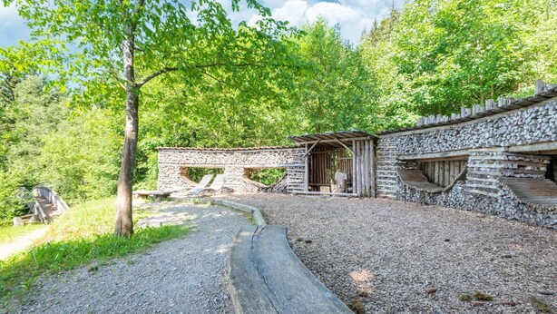 A rustic stone building with a wooden structure adjacent to it, surrounded by a gravel path and lush greenery. - Apartment Kirchbichl near Wildschönau Ski Slope (Kirchbichl)
