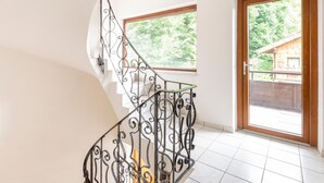 A staircase with ornate metal railings and a view of a wooden cabin through a glass door. - Apartment Kirchbichl near Wildschönau Ski Slope (Kirchbichl)