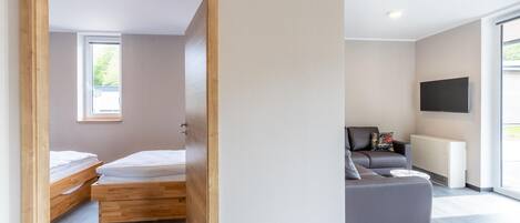 Ein modernes Zimmer mit einem Bett, einem grauen Sofa und einem Fernseher.