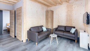 A modern living room with two sofas, a small round table, and a white cabinet. - Komfortables Bungalow am Kronenburger See mit Terrasse (Hallschlag)